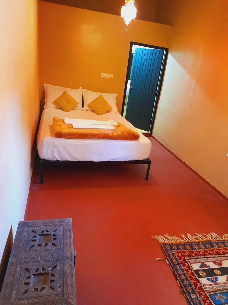 Double or Twin Room: the bed, an open dark door and a carved chest