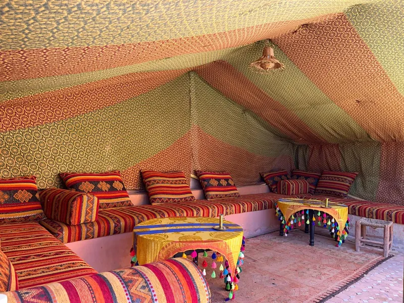 The lounge under a striped tent, with low sofas and cushions